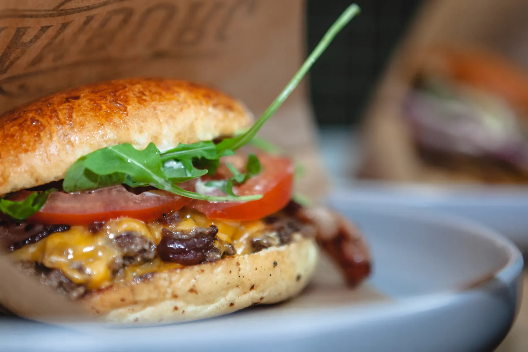 Foto de ejemplo: smash burger doble con cheddar fundido, tomate y rúcula, de cerca